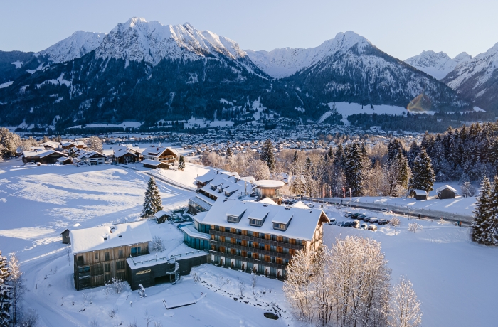 Verschneites Hotel in Oberstdorf mit Blick auf die winterliche Allgäuer Berglandschaft.