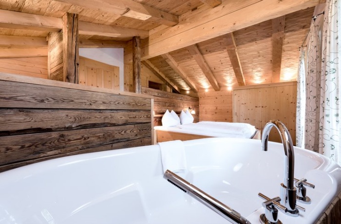 Hotelzimmer mit freistehender Badewanne: Gemütliches Holzinterieur im Hotel Puradies