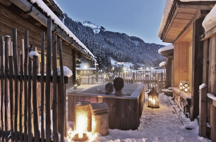 Die schönsten Chalets & Apartments: Ein Pärchen schaut aus einer Outdoor-Badewanne auf eine verschneite Berglandschaft.