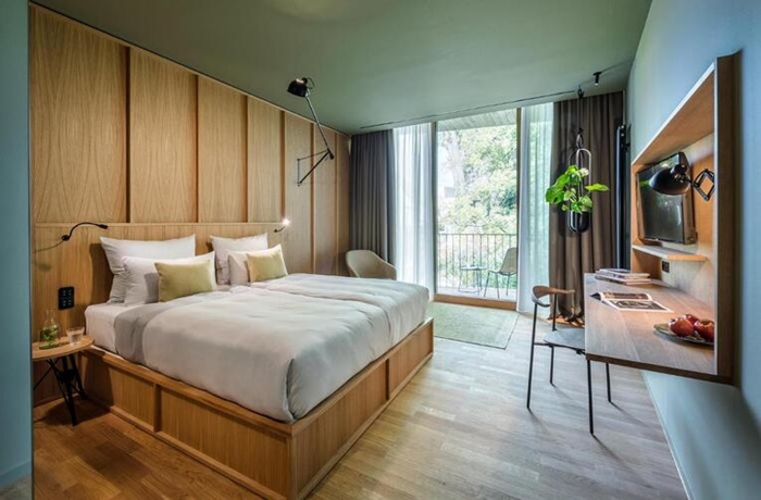 Hotelzimmer des La Maison Hotels in Saarlouis mit viel Holz und großem Bett