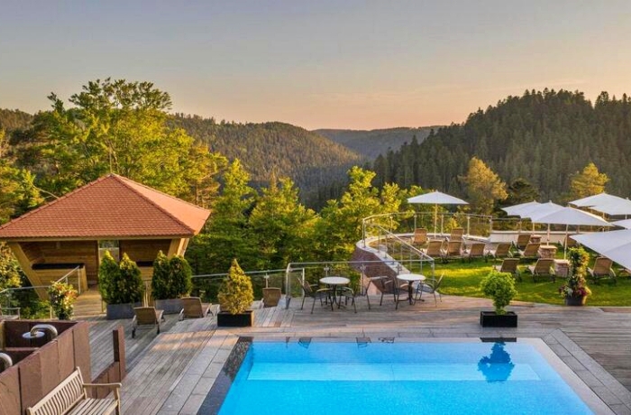 Sunset Spots gibt es in diesem Hotel viele: Wie hier der von einer Ruhe-Terrasse und Garten gesäumte Pool mit Blick über schier unendliche Tannenwipfel