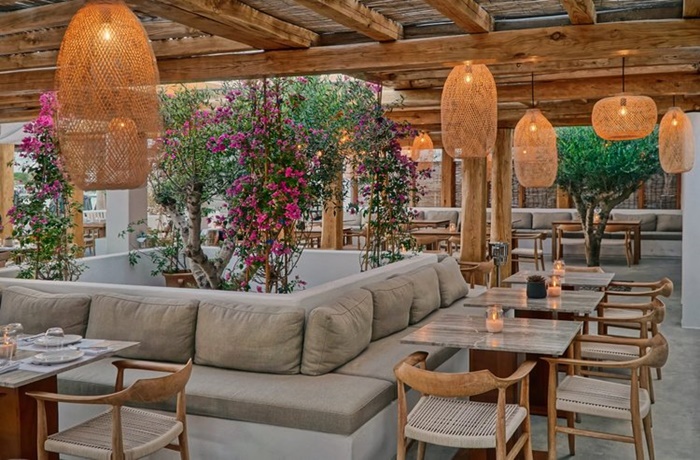 Eleganter Außen-Essbereich im Hotel Branco Mykonos, mit hellem Holz und Elementen aus Korb