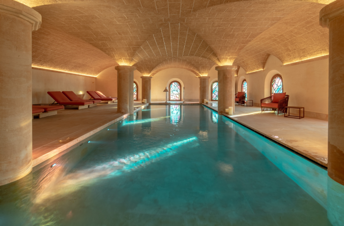 Innenpool in historischem Gewölbekeller mit Natursteinwänden und warmem Licht für eine entspannende Spa-Atmosphäre.
