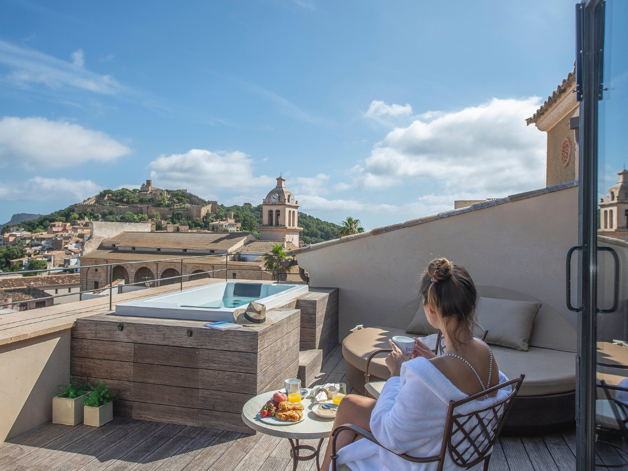 Hotelterrasse mit Whirlpool, Sitzmöbeln und Blick über die Stadt.