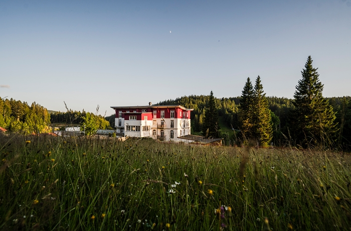 Hundefreundliche Hotels im Südschwarzwald: Blick auf das moderne Gebäude mit rotgestrichener Oberetage und Flachdach "Das Waldhotel am Notschreipass"