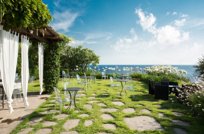 Grüner Garten mit Tischen, Garten des Hotel mit Ausblick auf das Mittel Meer