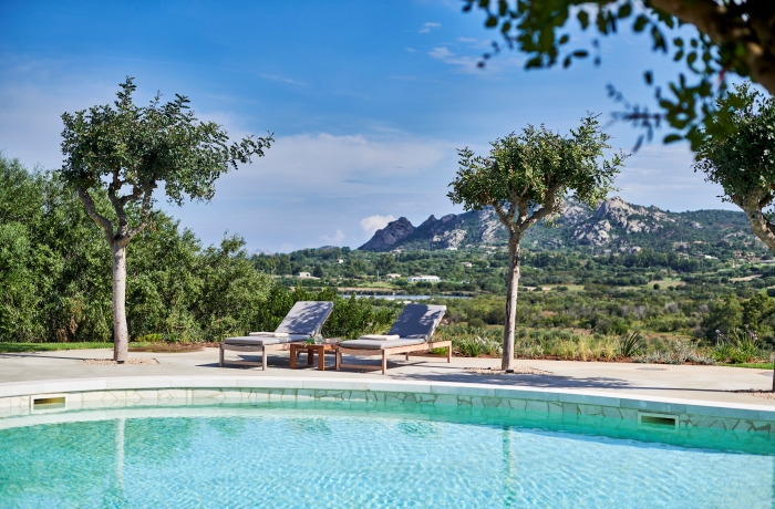 Mediterrane Villa mit stilvollem Außenpool, Natursteinarchitektur und gepflegter Gartenanlage inmitten der Landschaft Sardiniens.