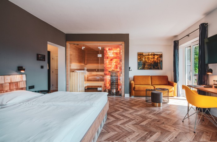 Gemütliches Hotelzimmer mit eigener Sauna, gelben Akzenten und stylischem Holzboden.