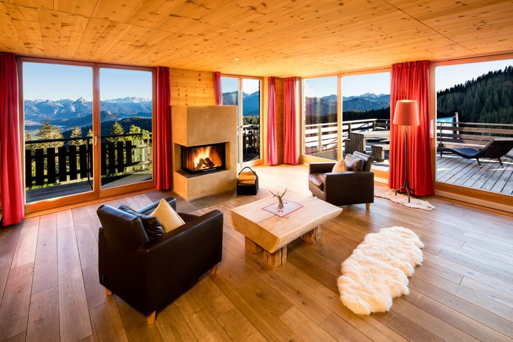 Alpin-gemütliche Hotelsuite mit Holzdecke und großen Fensterfronten mit Bergblick
