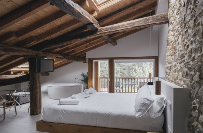 Hotelzimmer mit freistehender Badewanne und Holzbalken an der Decke im Hotel Boutique Nafarrola