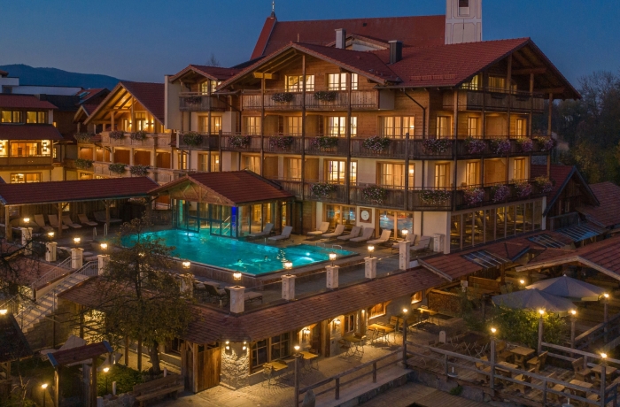 Stimmungsvoll beleuchtetes Alpenhotel am Abend mit Außenpool, gemütlichen Balkonen und warmer Wellness-Atmosphäre.