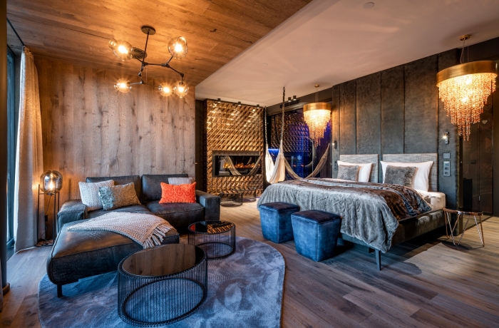 Luxuriöses Hotelzimmer mit Kamin, großem Bett und eleganter Einrichtung in warmen Farbtönen.