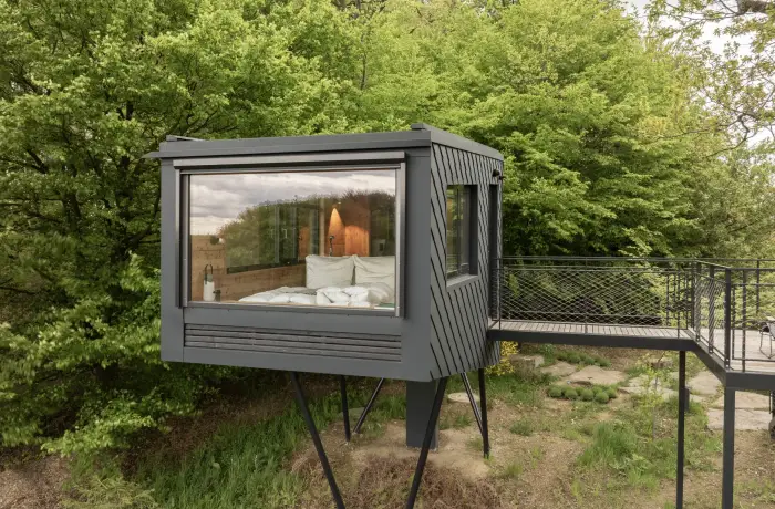 Baumhaushotel mit Bett hinter einer großen Glasfront für einen romantischen Ausblick