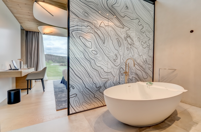 Design-Zimmer im Hôtel des Horlogers mit freistehender Badewanne und Panoramablick ins Grüne.