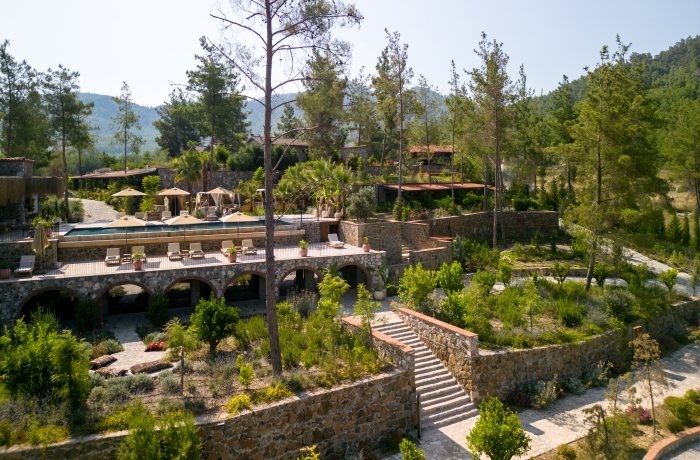 Terrassenbereich des IZZ Getaway Resorts mit Pool und Liegen in mediterraner Natur.