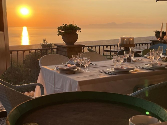 Vom festlich gedeckten Tisch blickt man auf einen spektakulär feuerfarbenen Sonnenuntergang.