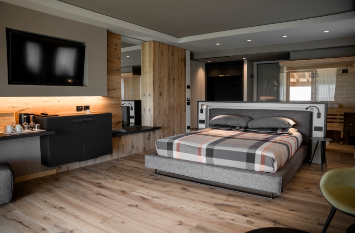 Modernes Hotelzimmer mit offenem Design, großem Doppelbett, Holzelementen und hochwertiger Ausstattung für einen stilvollen Aufenthalt.