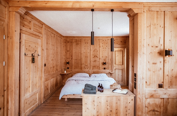 Hotel im Unterengadin: Blick in ein mit hellem Holz verkleidetes Hotelzimmer im Hotel ÜJA in Scuol