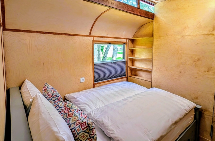 Kleines gemütliches Holzhaus mit schlichtem Schlafzimmer und warmem, minimalistischem Innenraum.
