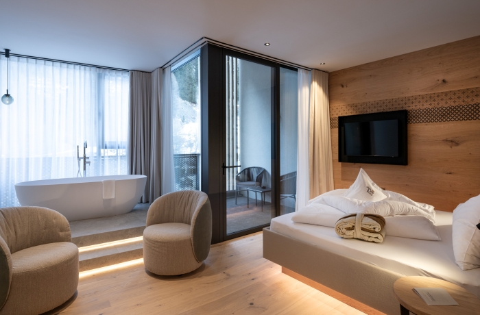 Modernes Zimmer der Die Post am Ortler mit freistehender Badewanne, Balkon und alpinem Design.