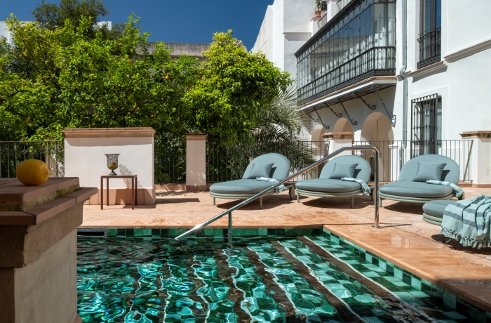 Stilvoller Innenhof mit elegantem Pool, komfortablen Sonnenliegen und mediterranem Flair inmitten historischer Architektur.