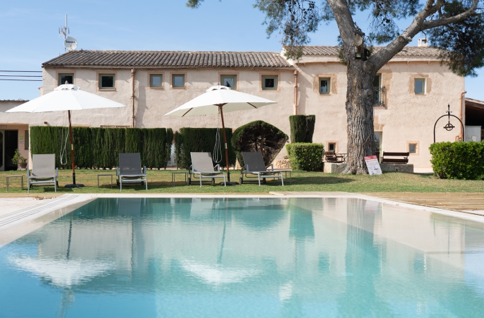 Mediterranes Landhotel mit großzügigem Außenpool, gepflegten Gartenanlagen und traditionellen Natursteingebäuden. Die ruhige Lage inmitten der mallorquinischen Landschaft macht das Anwesen zu einem idealen Rückzugsort für Erholung und Entspannung.