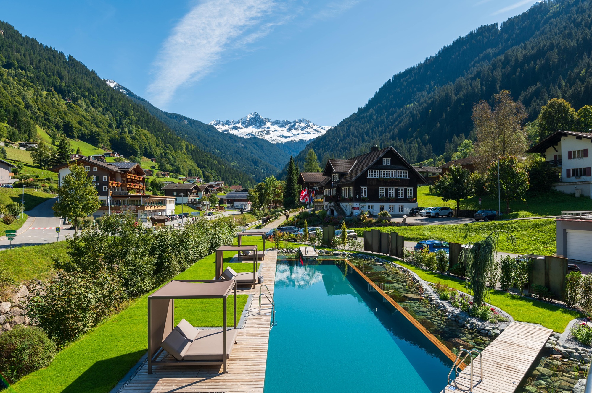Der Naturpool des Hotel Bergkristall Montafon liegt eingebettet in die beeindruckende Berglandschaft des Montafons. Stilvolle Daybeds, gepflegte Gartenanlagen und der Blick auf die schneebedeckten Gipfel der Alpen schaffen eine ruhige Wohlfühlatmosphäre für entspannte Urlaubstage.