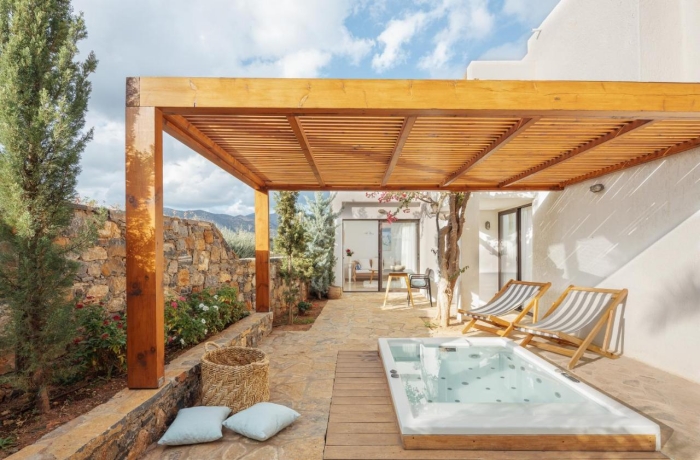 Außenbereich einer Suite mit Whirlpool, Pergola, Sonnenliegen und Zugang zum Zimmer.