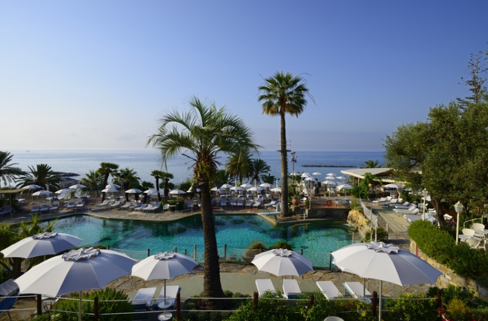 Hotelpool mit Palmen, Weissen Schirmen, Hotel & Pool mit Ausblick auf das Meer vor Italien