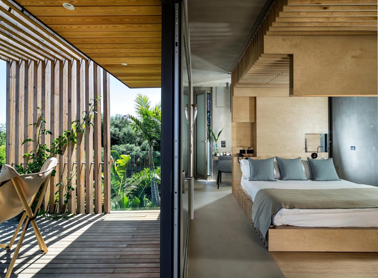 Modernes Zimmer im Donna Carmela Boutique Hotel mit Holzdesign, Terrasse und mediterranem Gartenblick.