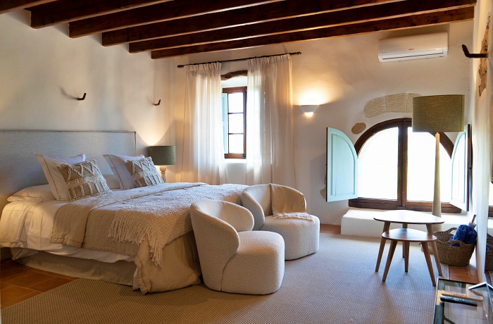 Hotelzimmer: Ein Mix aus modernen Designmöbeln und rustikalen Elementen wie dunkel-hölzernen Deckenbalken und Rundbögenfenstern