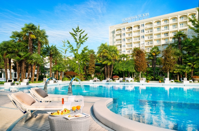 Eleganter Hotelpool mit Palmen und mediterranem Flair vor dem Grand Hotel Trieste & Victoria in Italien.