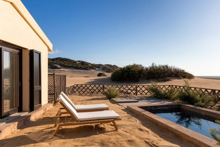 Eingezäunter Bereich inmitten der Dünen mit Sonnenliegen und Pool