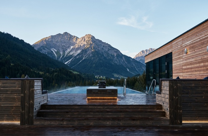 Infinity-Pool des A-ROSA Ifen Hotel Kleinwalsertal mit atemberaubendem Blick auf die umliegenden Berge, modernes Holzdesign und klare Bergluft in ruhiger Atmosphäre.