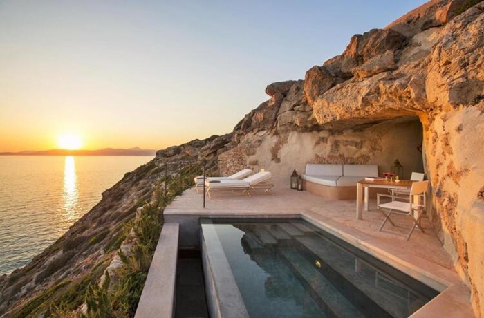 Terrasse im Felsen mit Privatpool und Lounge Möbeln. Im Hintergrund geht die Sonne unter.