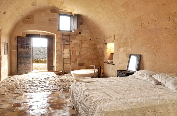 Top 10 Hotels in Italien: Sextanio Le Grotte Della Civita, Zimmeransicht mit Bett und Wanne, altes Gemäuer