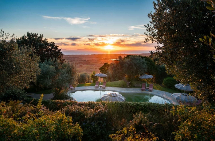 Naturpool im Relais Vedetta mit Olivenbäumen, Sonnenuntergang und Panoramablick über die toskanische Küstenlandschaft.