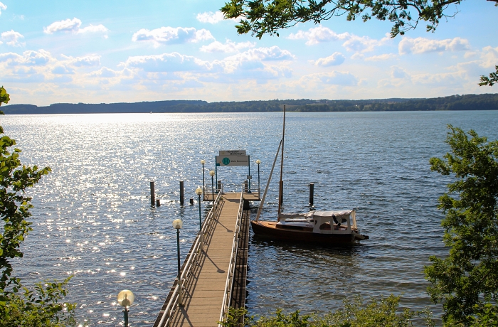 Steg mit festgemachtem Boot n der Nähe des Seehotel Heidehof, außernrum die in der Sonne glitzernde Wasserfläche