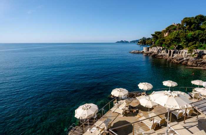 Badeurlaub: Ein luxuriöses Hotel, das majestätisch an einer felsigen Küste thront, bietet einen atemberaubenden Blick auf das azurblaue Meer.