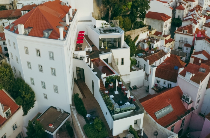 Luftaufnahme eines modernen Boutique Hotels mit großzügigen Dachterrassen, Rooftop-Pool und Blick über die historischen Gassen einer mediterranen Altstadt.