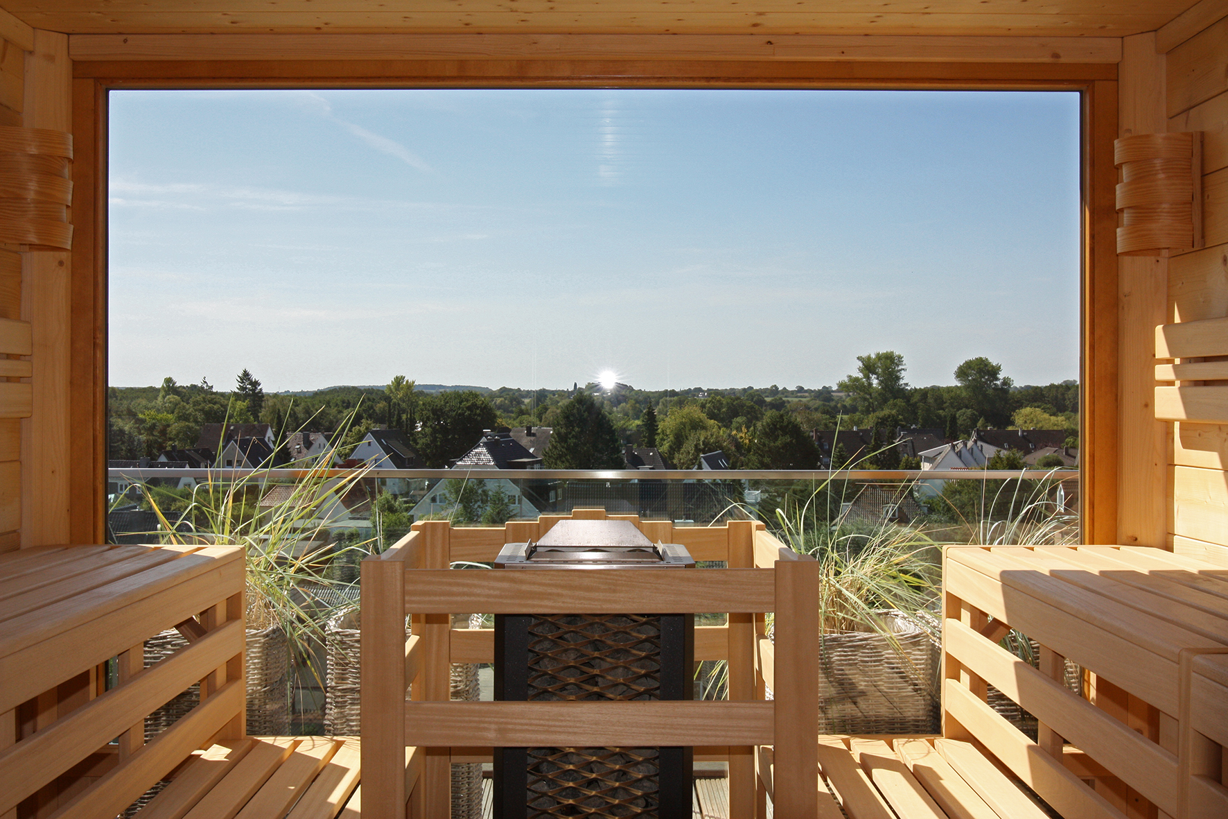 Moderne Holzsauna mit Panoramafenster und Blick über eine grüne Landschaft – ein stilvoller Rückzugsort für entspannte Wellnessmomente.