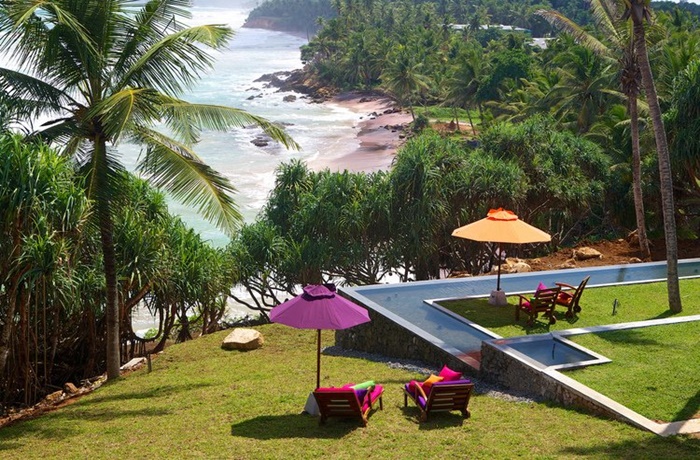 Panoramablick auf Pool, Schirme, Palmen und Meer