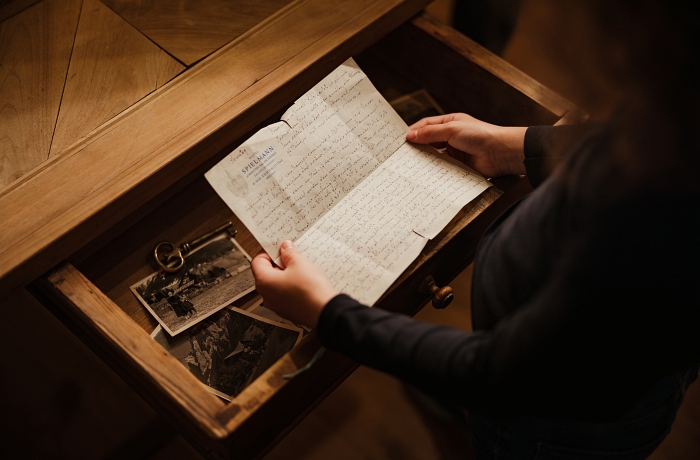 Ein historisches Dokument wird von zwei Händen gehalten - es geht um das Hotel Spielmann in Ehrwald