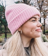 Reisebloggerin Anna Brouwers posiert lächelnd mit rosa Wollmütze, im Hintergrund befindet sich eine herbstliche Naturlandschaft