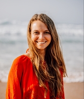Top 50 Reiseblogs: Christine Neder posiert in roter Bluse am Strand