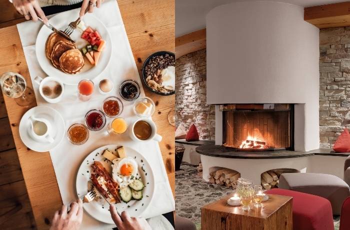 Reichhaltiges Frühstück auf einem Holztisch und gemütlicher Kamin mit brennendem Feuer.