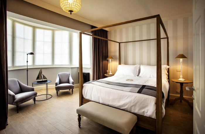 Elegantes Hotelzimmer mit Himmelbett und gemütlicher Sitzecke im stilvollen Boutique-Ambiente.