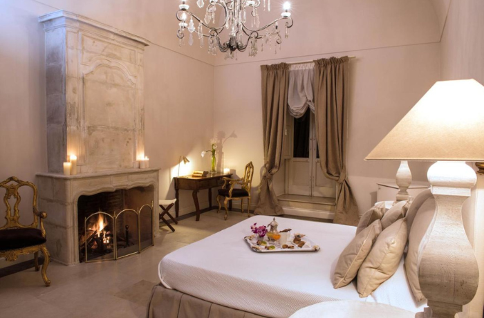 Romantisches Hotelzimmer mit historischem Kamin, Kristallleuchter und elegantem klassischem Ambiente.