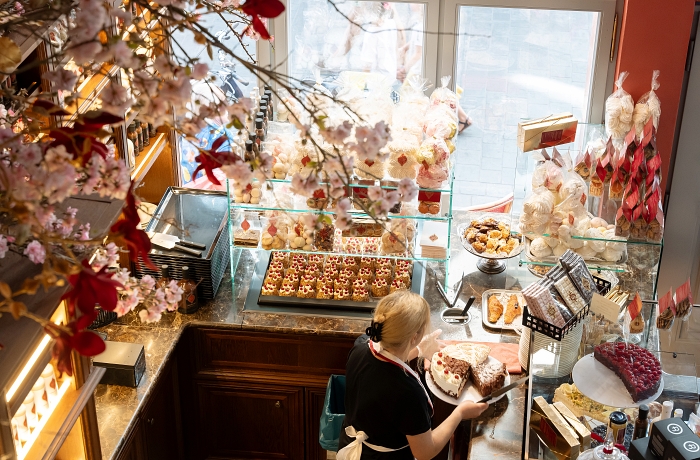 Geheimtipp Frankfurt: Vogelperspektive in den Verkaufsraum einer Frankfurter Konditorei, die auch den Klassiker Frankfurter Kranz anbietet, eine Mitarbeiterin ordnet Kuchenstücke an