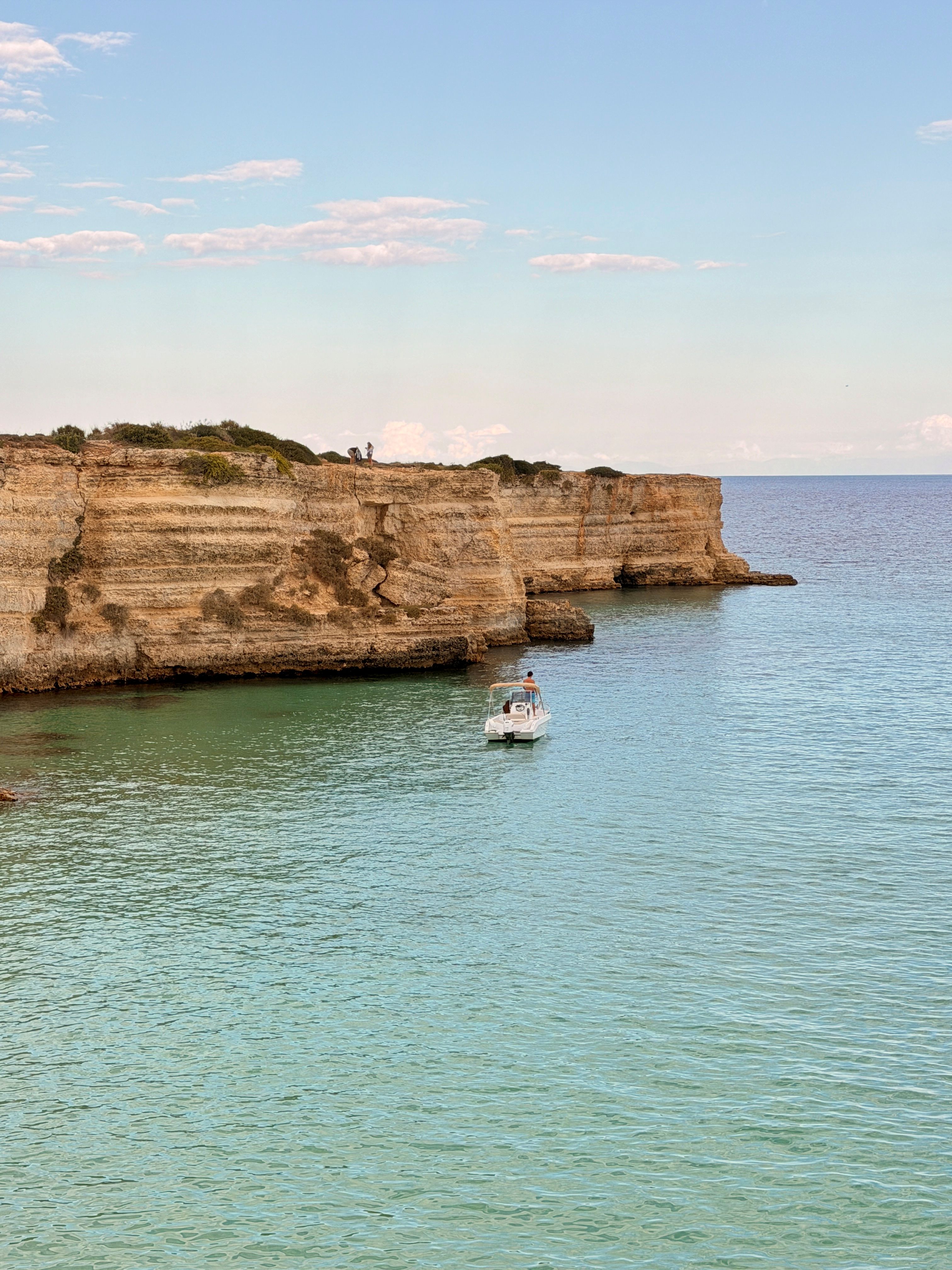 Blick auf eine Bucht mit einem einzelnen Motorboot, im Hintergrund heben sich Klippen ab